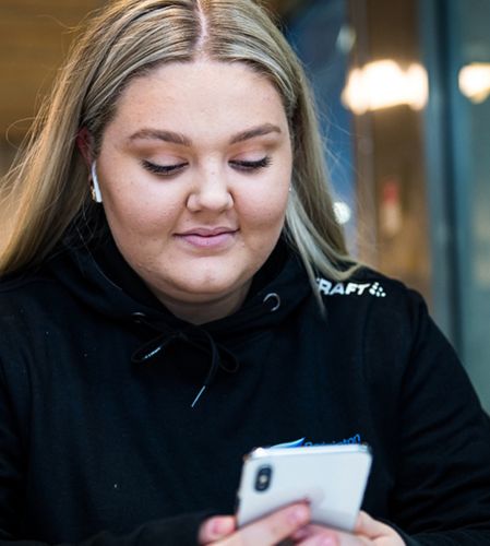 Kvinna kollar på mobil och ler