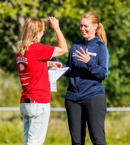 Två ledare diskuterar och skrattar på fotbollsplanen – och länk till Kunskapsarenan
