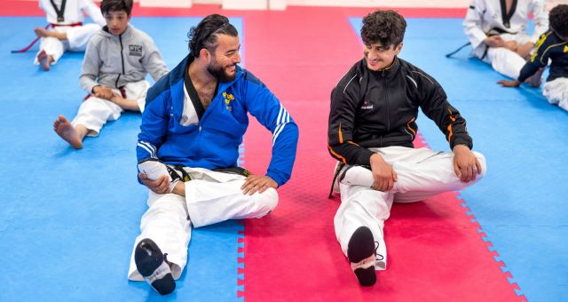 Tränare och ung kille stretchar under taekwondoträning