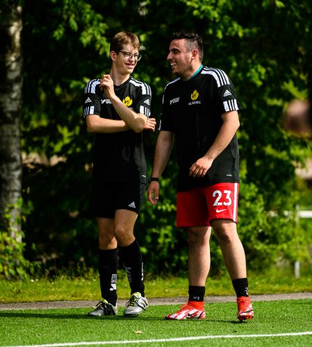 Två fotbollsspelande män står och pratar på en fotbollsplan